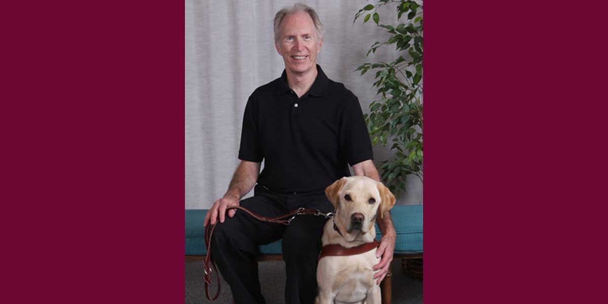 Michael Nelipovich seated with his guide dog.