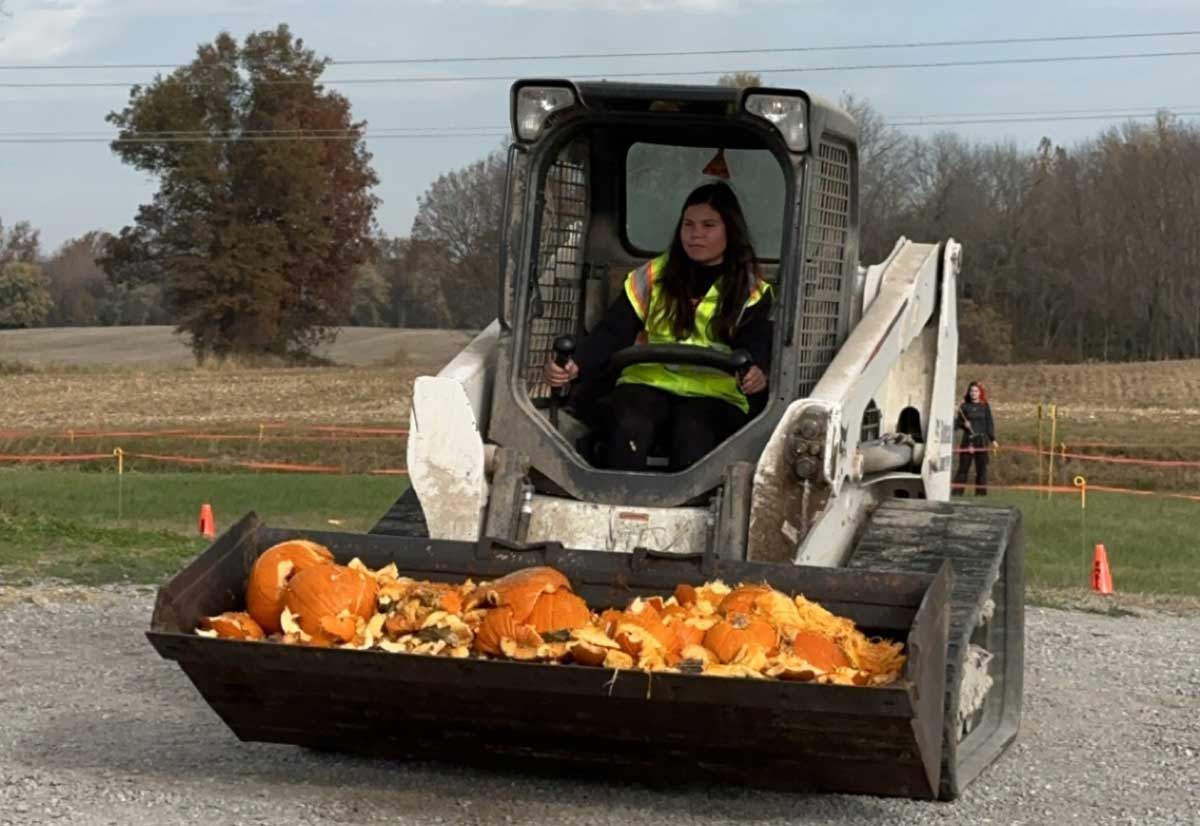 Image of a woman using heavy equipment to haul pumpkins