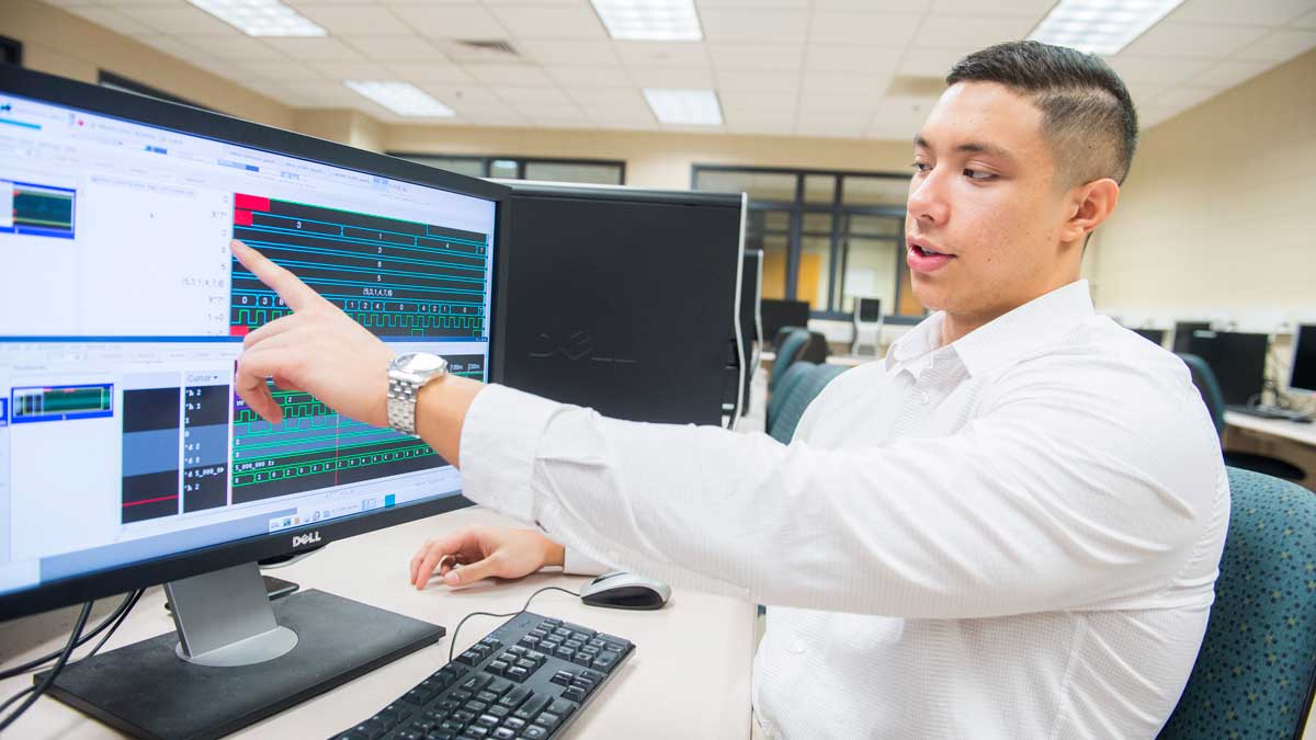 A man is seen gesturing toward a computer screen