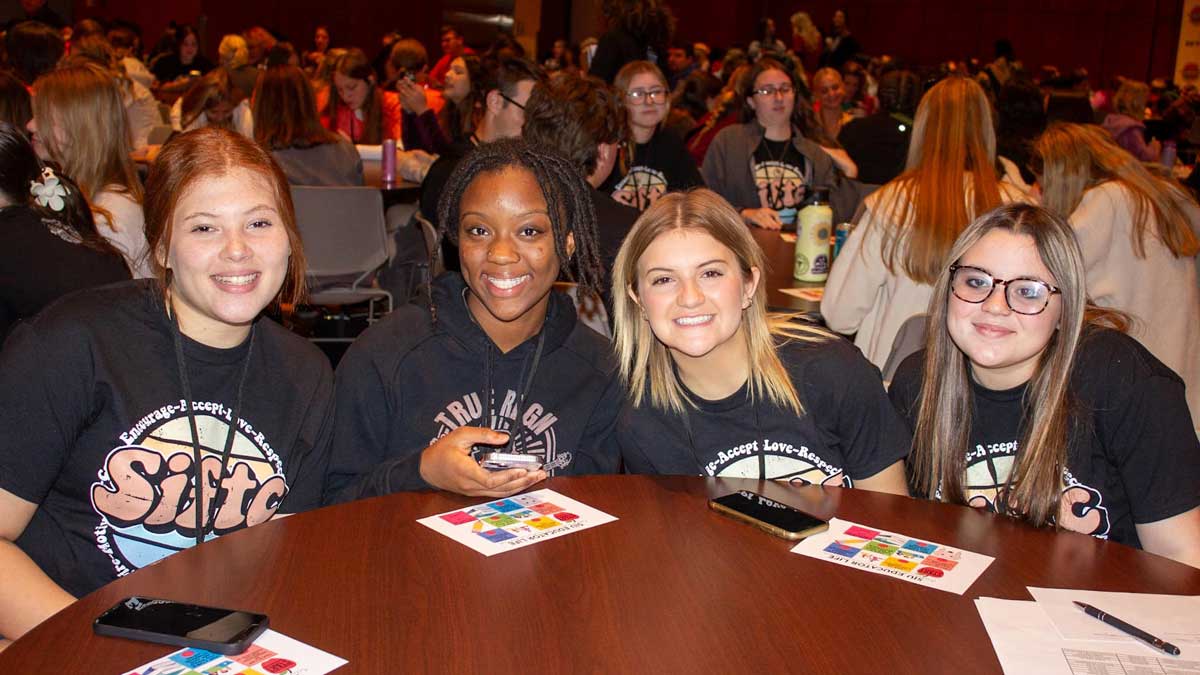 A group of students pose for a picture while seated around a table