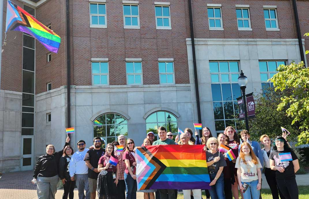 Group of people holding a rainbow pride flag