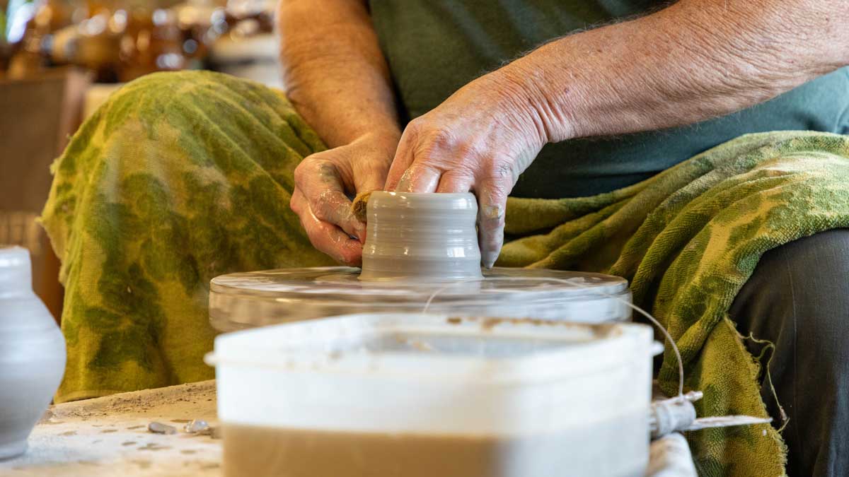 A person is working clay on a potters wheel.