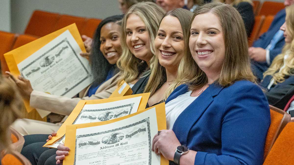 Four young women display their certificates during the swearing in ceremony.