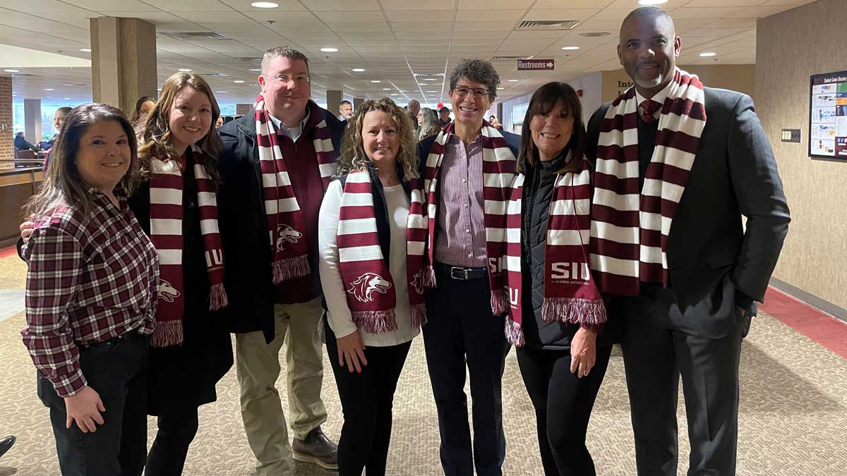 A group of people wearing maroon and white scarves.