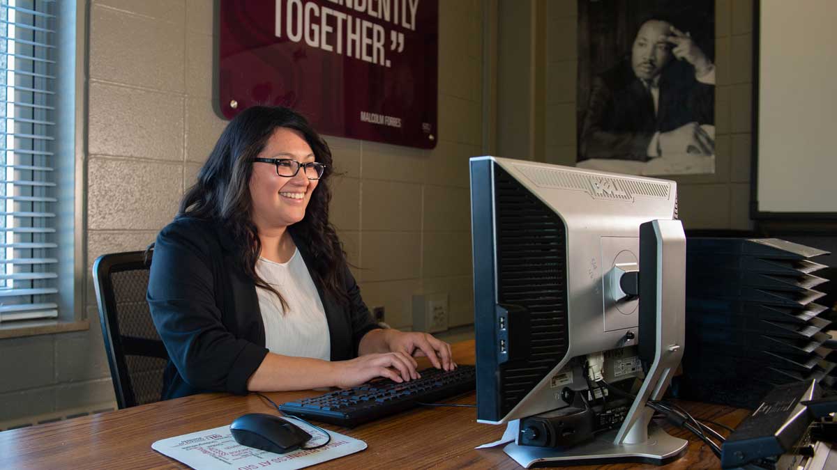 A woman seated at a desk while working at a computer.