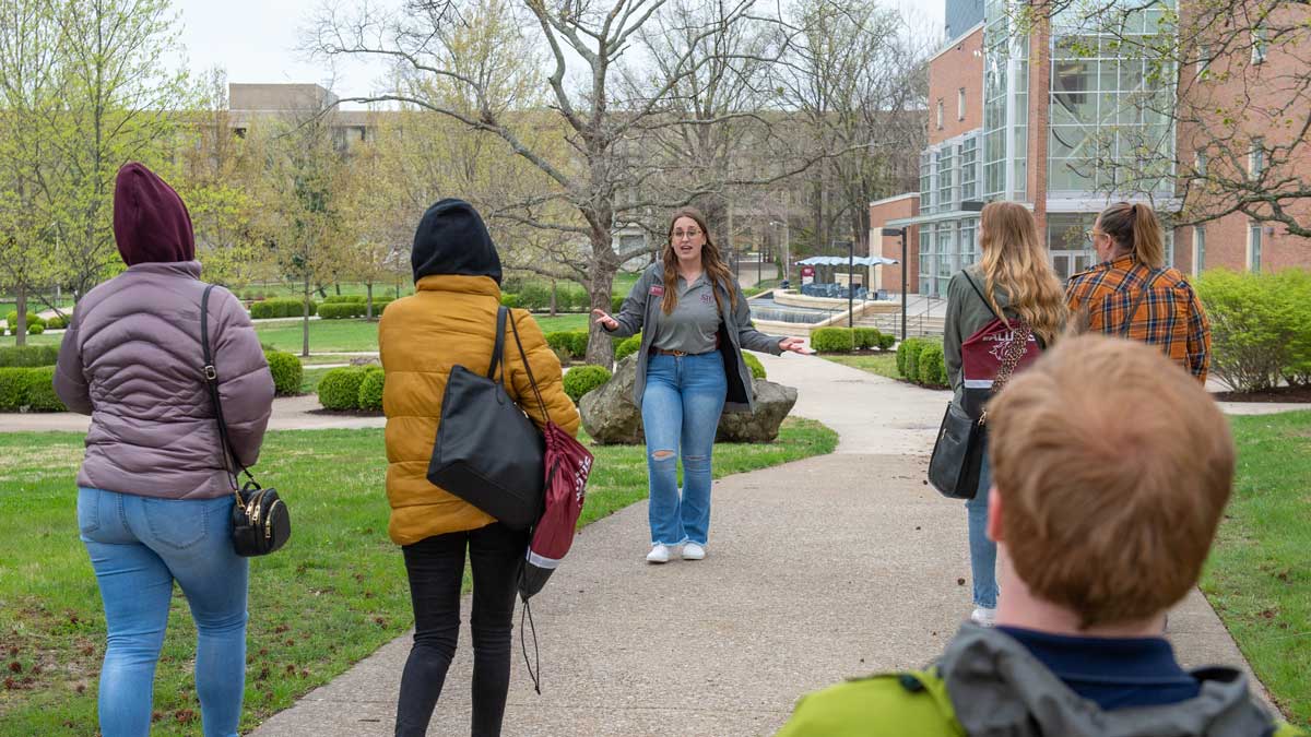 A student conducts a tour of campus to new students.