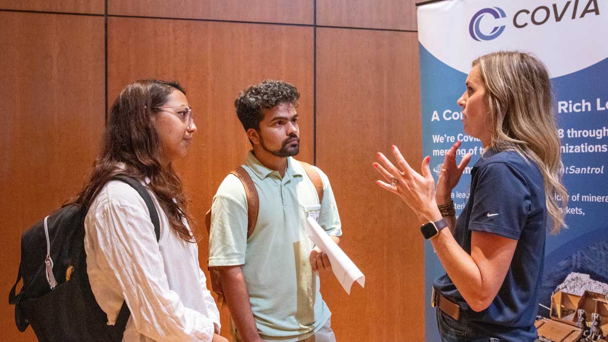 Students speaking with a presenter at a job fair.