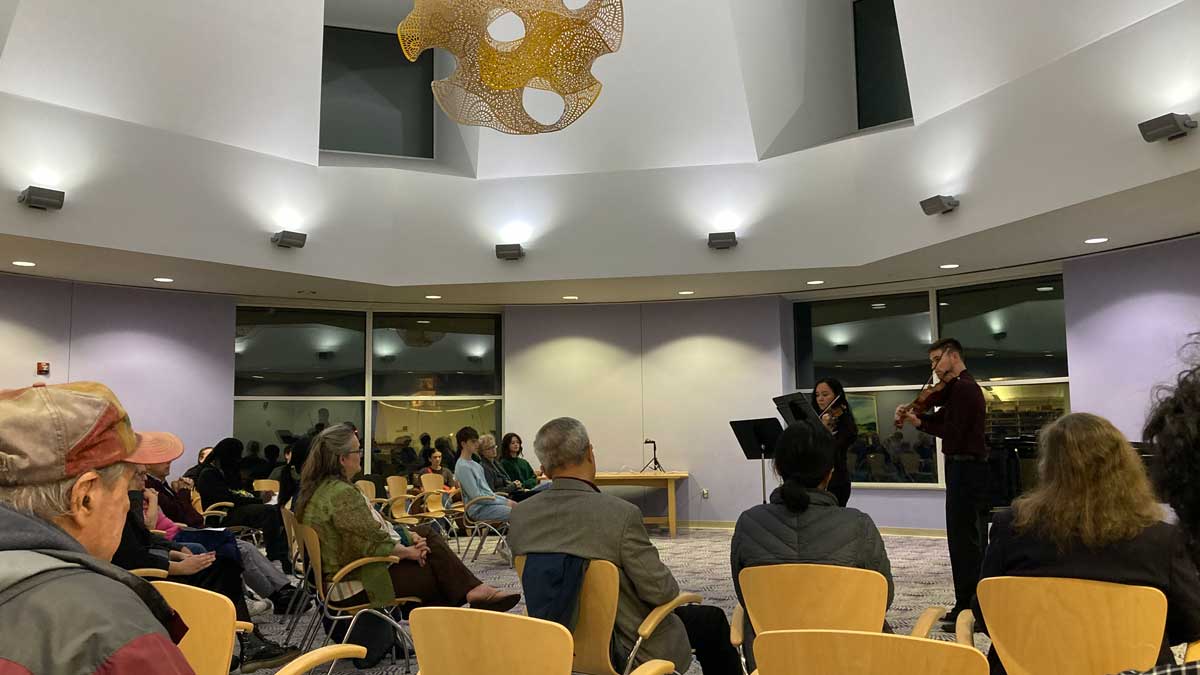 A group of people are watching and listening to a small concert experience.