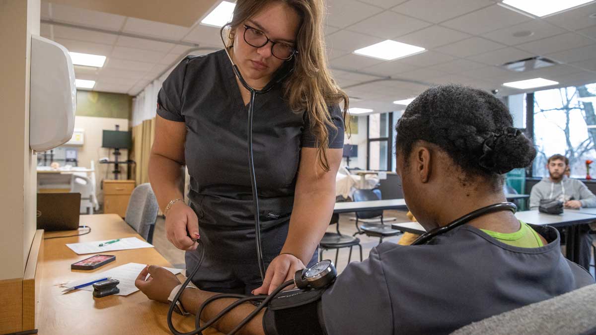 Two nursing students practice taking blood pressure.