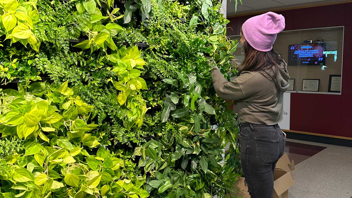 A woman stands in front of a living wall.