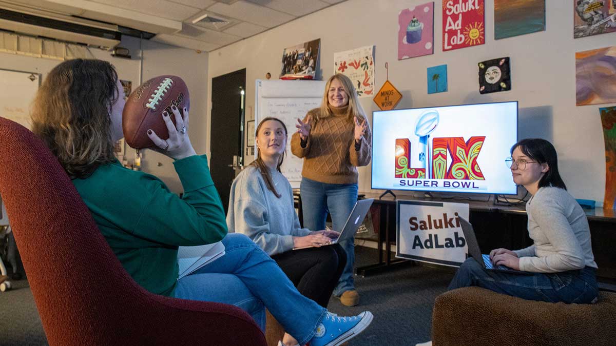 A group of students tossing a football while watching TV.