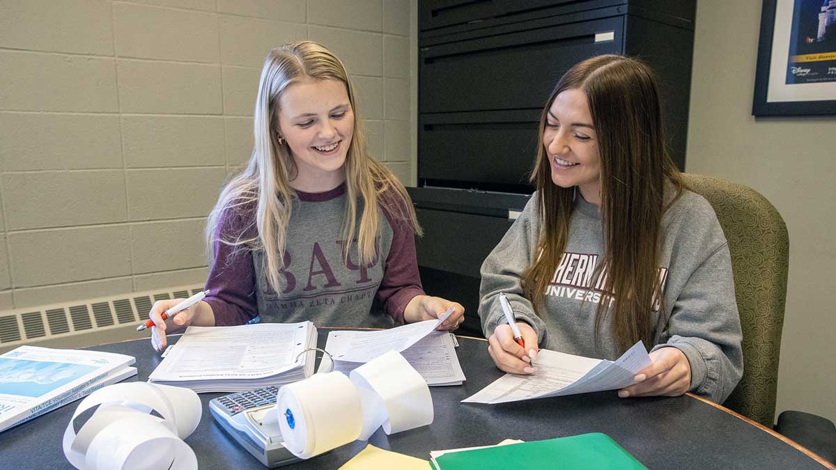 Two women review paperwork.