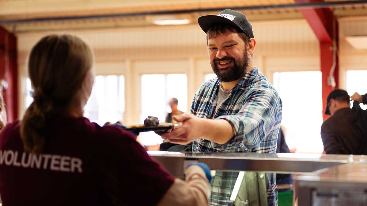 A volunteer is serving pancakes.