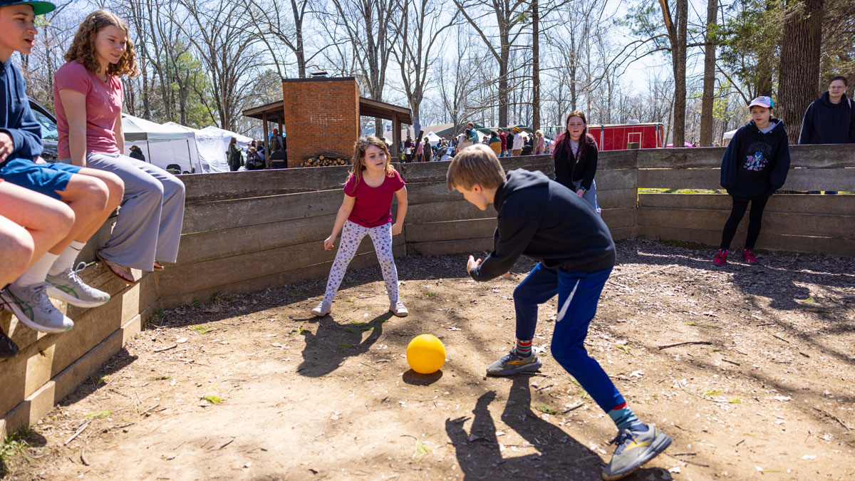 Children playing with a ball while others watch.
