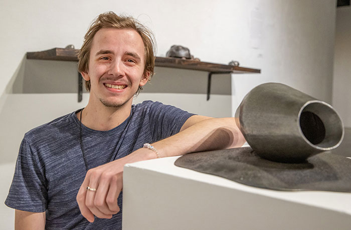 A man stands in front of an art exhibit.