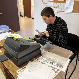 A young man works on a cash register.