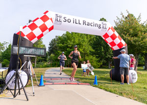 A woman crosses a finish line for a race.