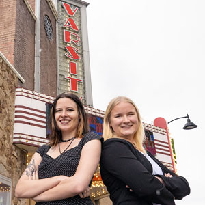 Two women stand outside the Varsity Theater.