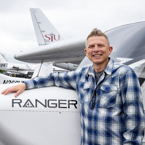A man is leaning against an airplane.