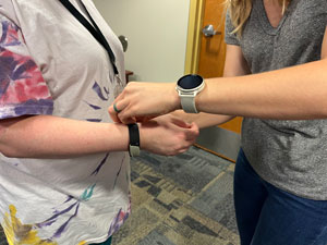 Someone places a FitBit on a persons arm.