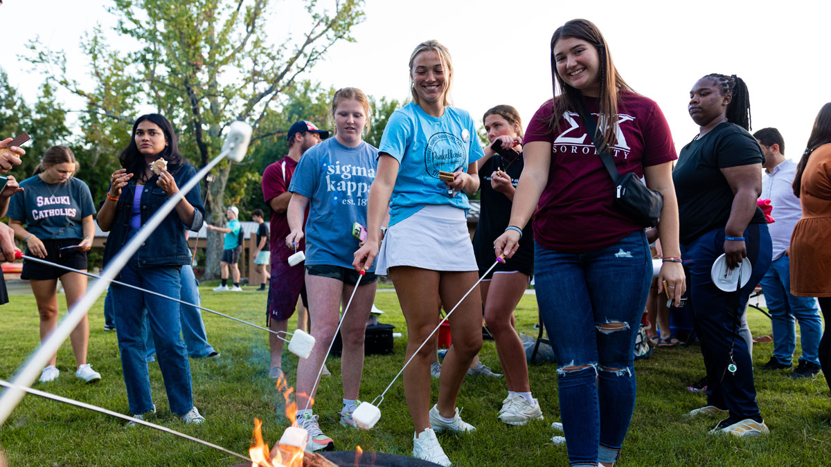 A group of students roasting marshmallows.