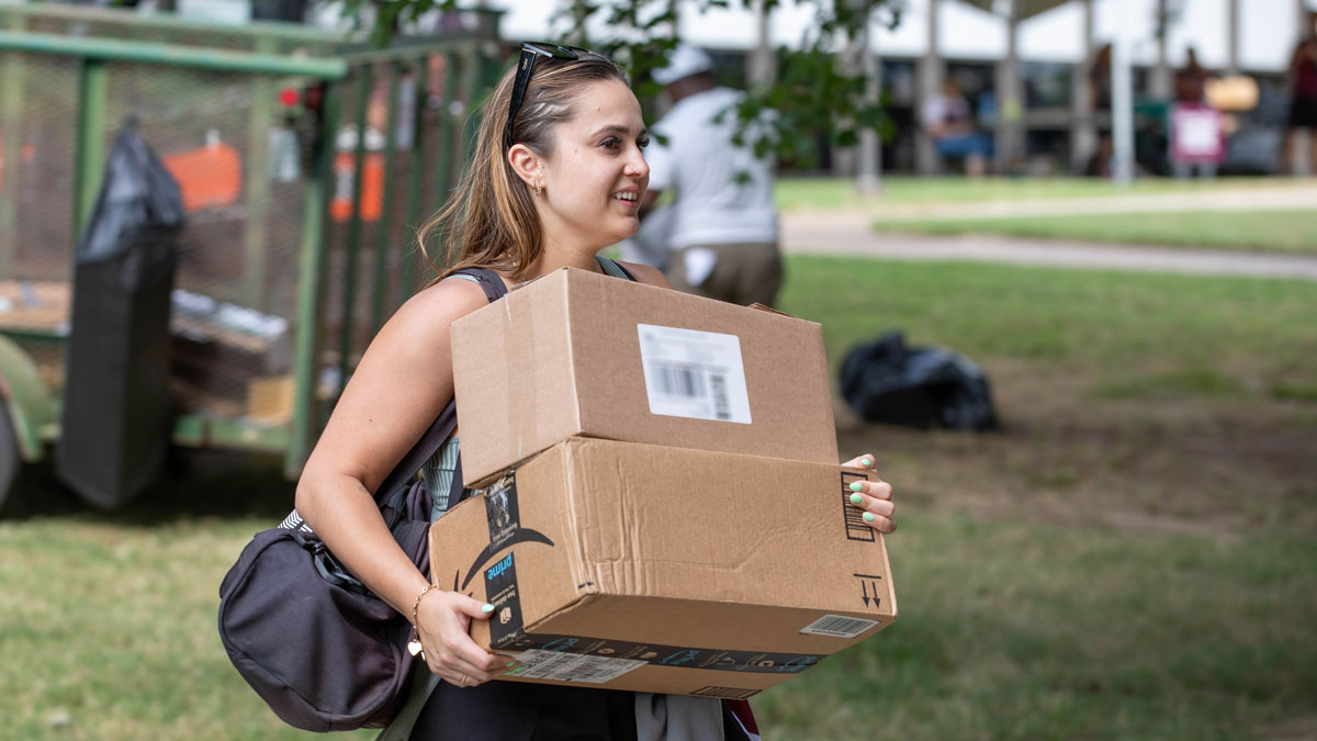 A woman carrying boxes at move in, on campus.