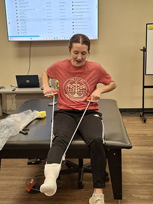 A woman is using an assistive device to put on a sock.