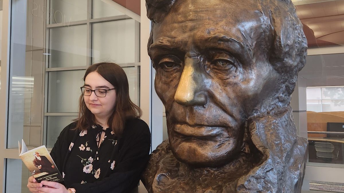 A woman stands next to a statue of Abraham Lincoln.