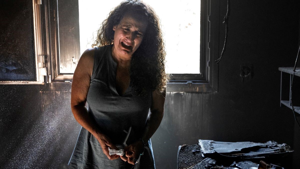 A woman cries while standing in a burned out room.