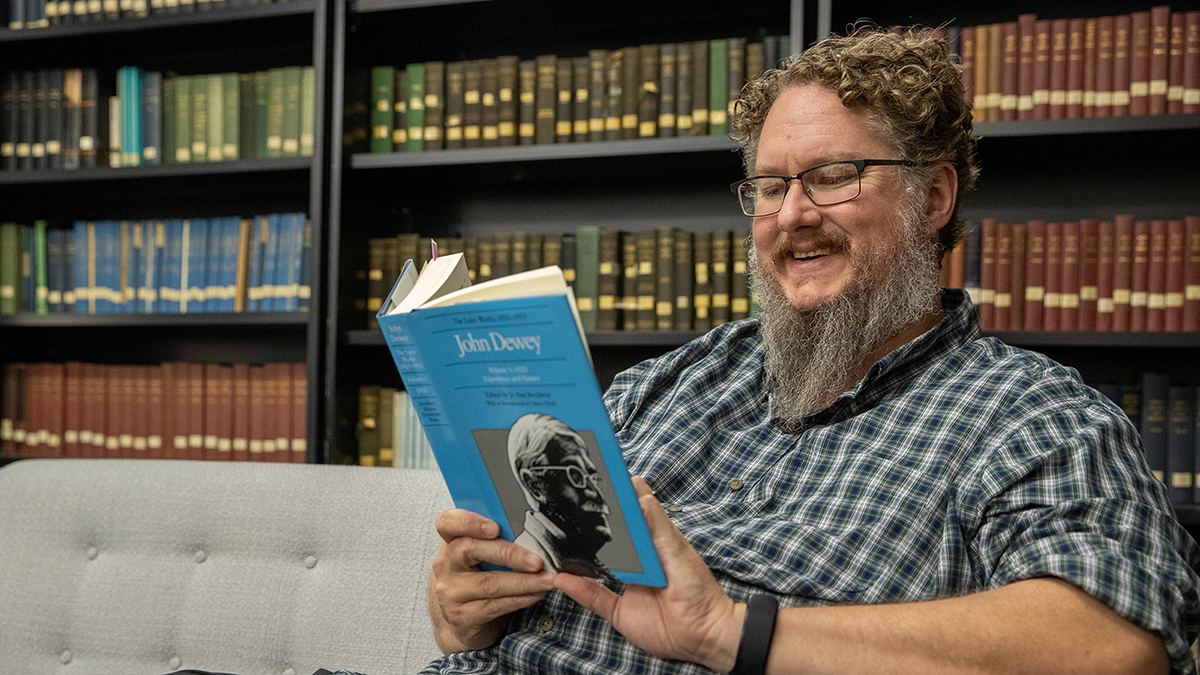 A man is reading a book in a library.