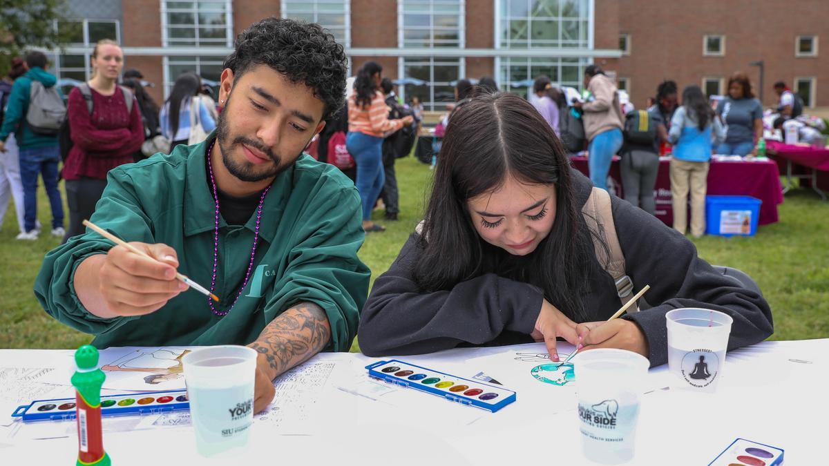 Two students enjoying painting in front of Morris Library
