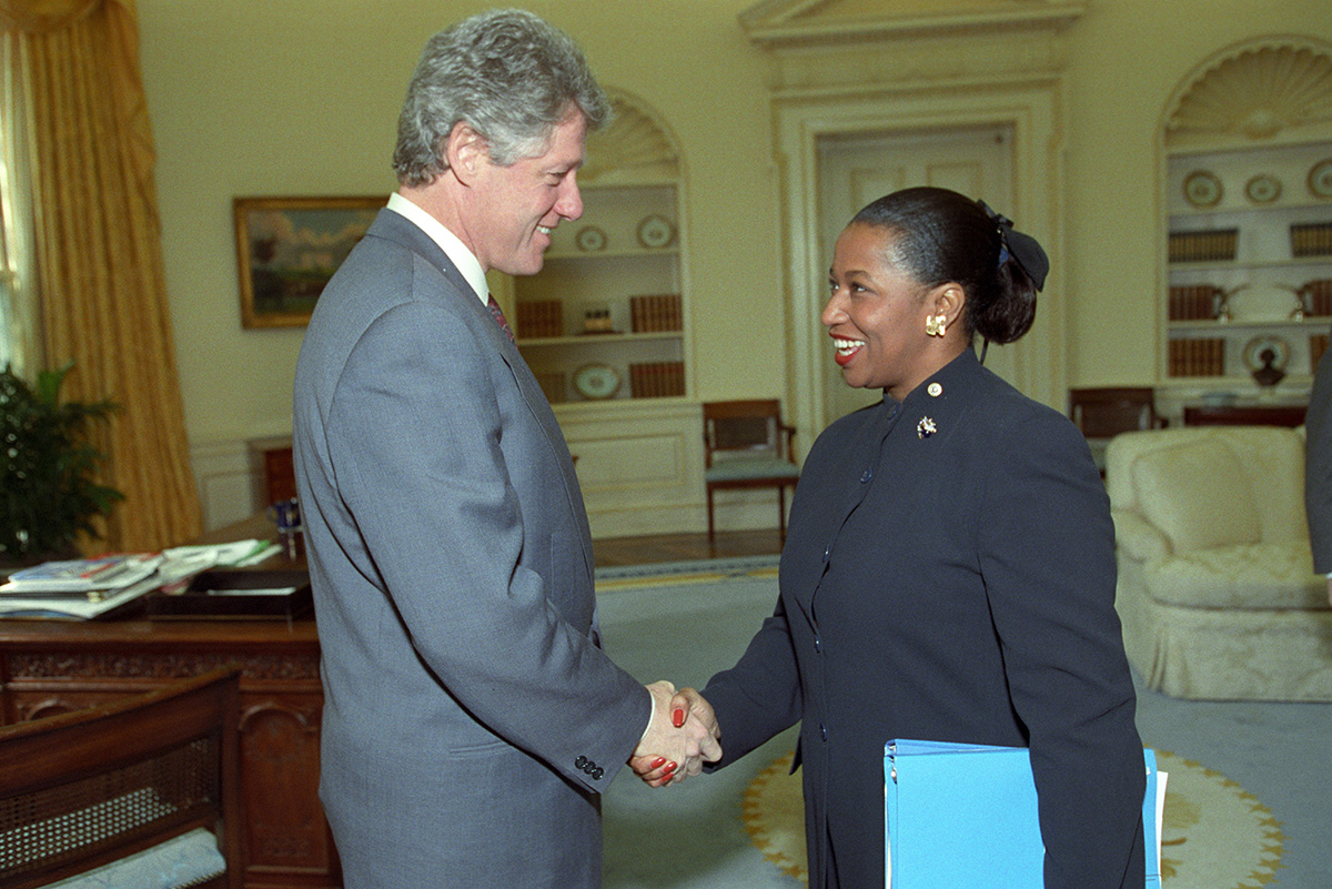 Former President Bill Clinton and Carol Moseley Braun are shaking hands in the Oval Office.