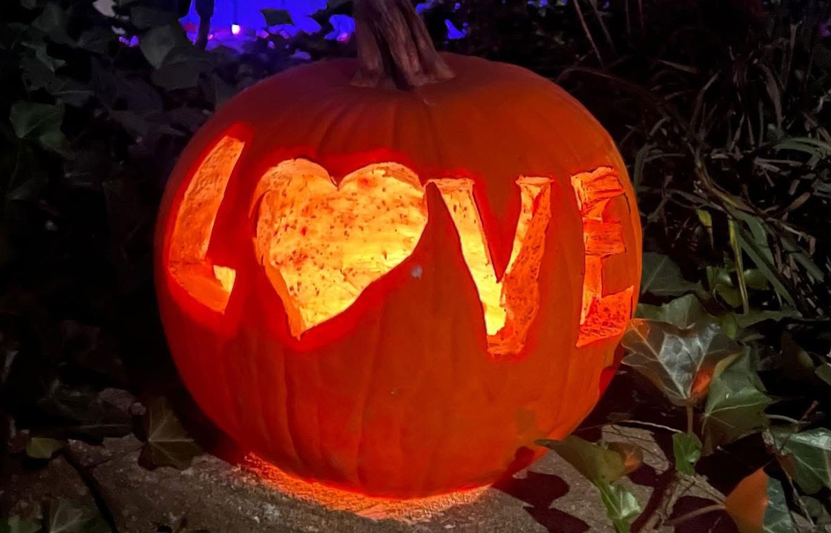 The word love is seen carved into a pumpkin.
