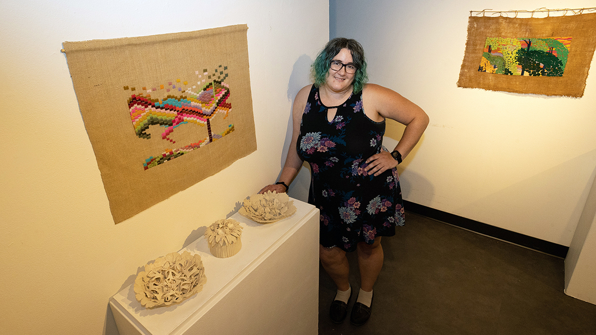 A person poses with artwork on display.