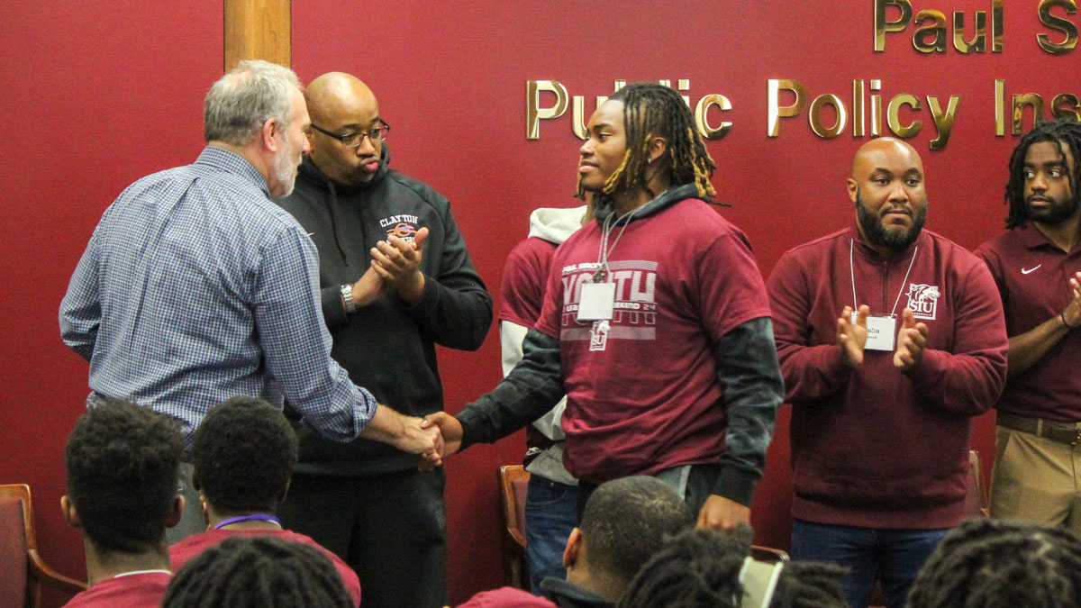 A student receives an award from John Shaw of the Paul Simon Public Policy Institute.