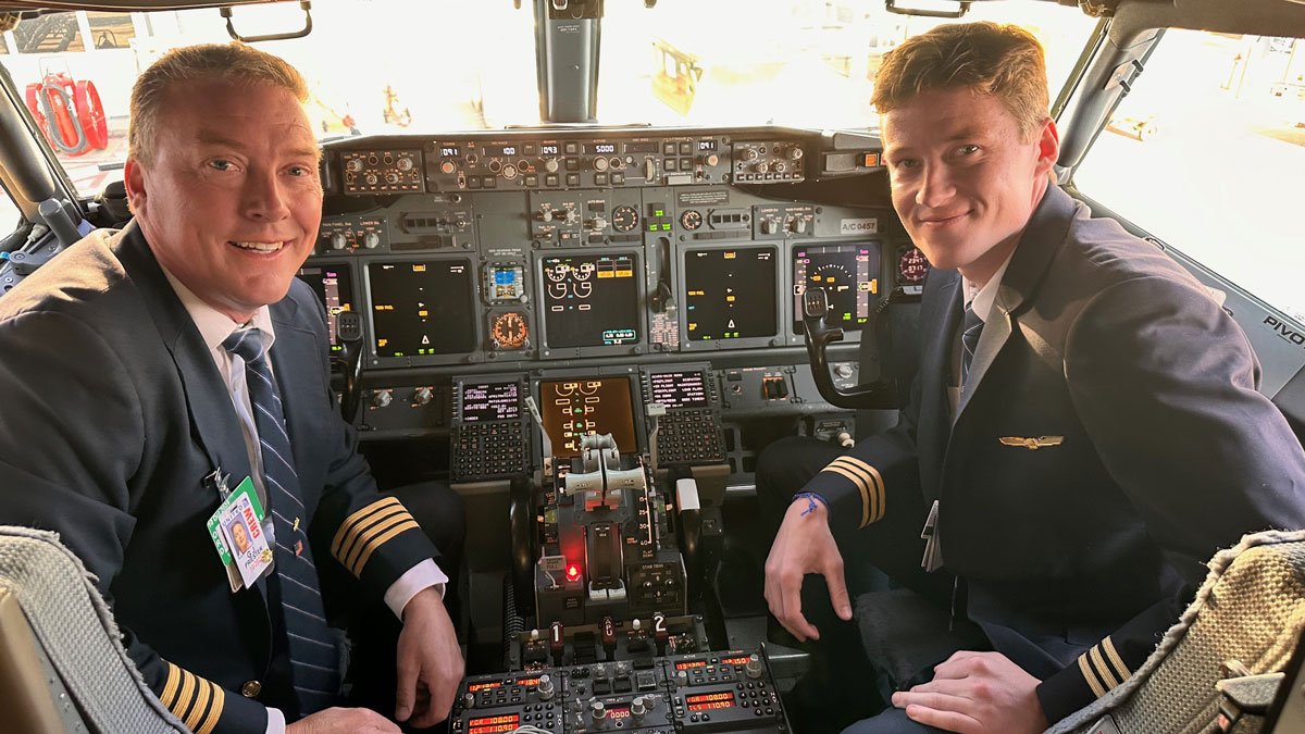 Father and son pilots pictured in the cockpit of an airplane.