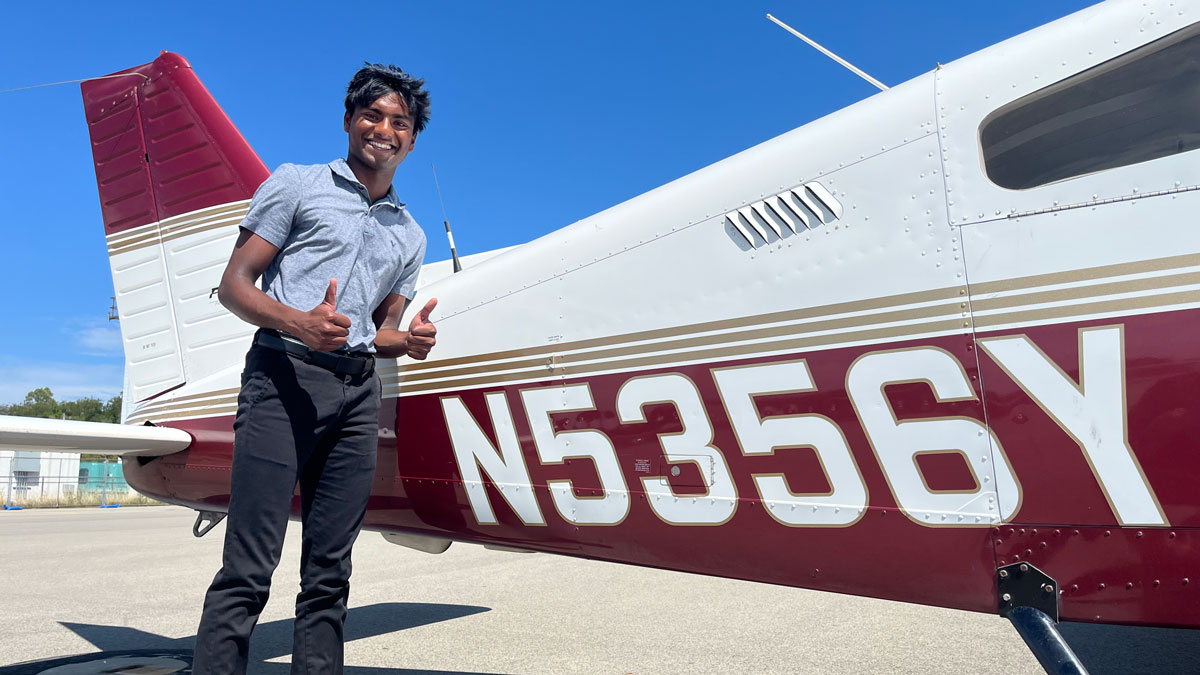 An SIU aviation student stands next to an airplane.