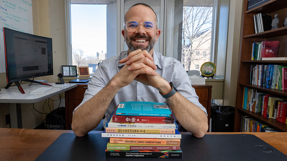 A man seated behind a stack of books. 