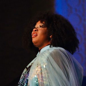 A woman, on stage, singing an opera.