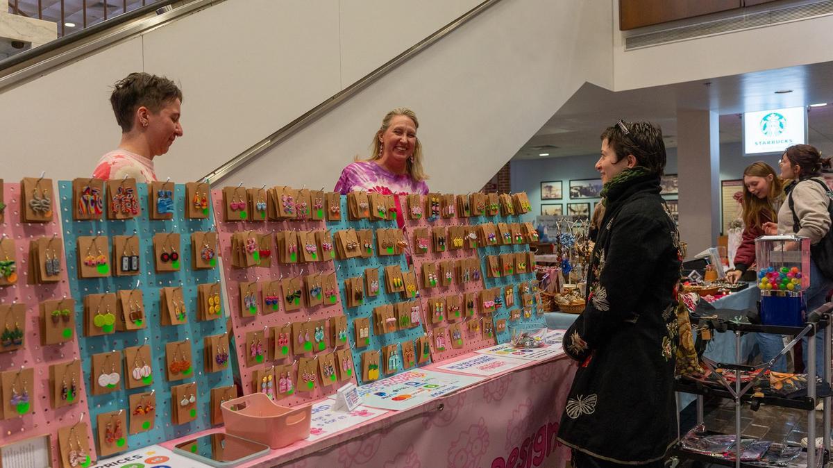 Patrons stop to view jewelry at a craft sale.