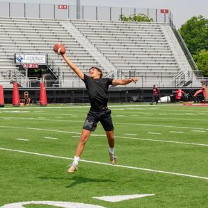 A child leaping to catch a football.