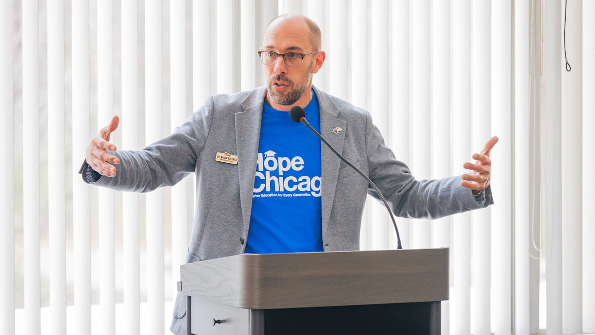 A man is standing at a podium. His shirt says Hope Chicago.