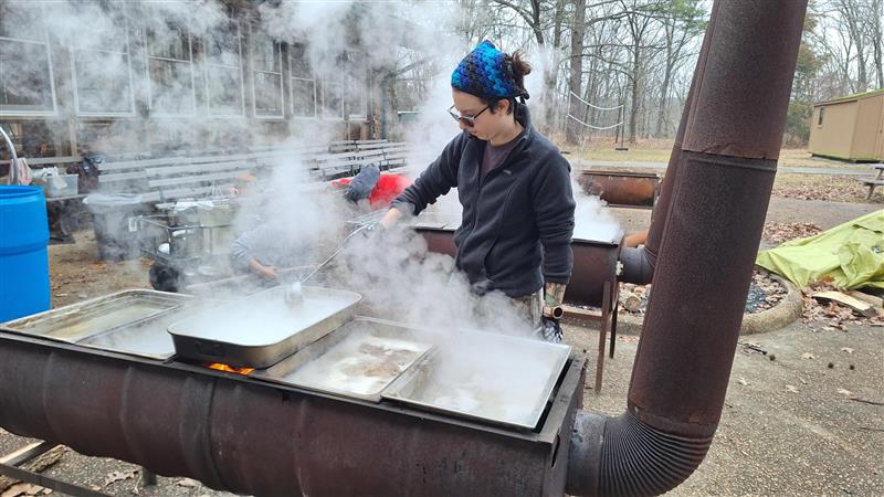 A person is boiling sap to make maple syrup.