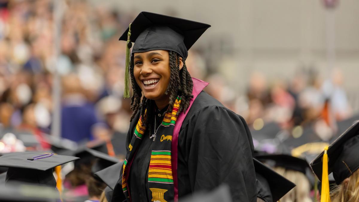 A student is smiling while participating in commencement at SIU Carbondale.