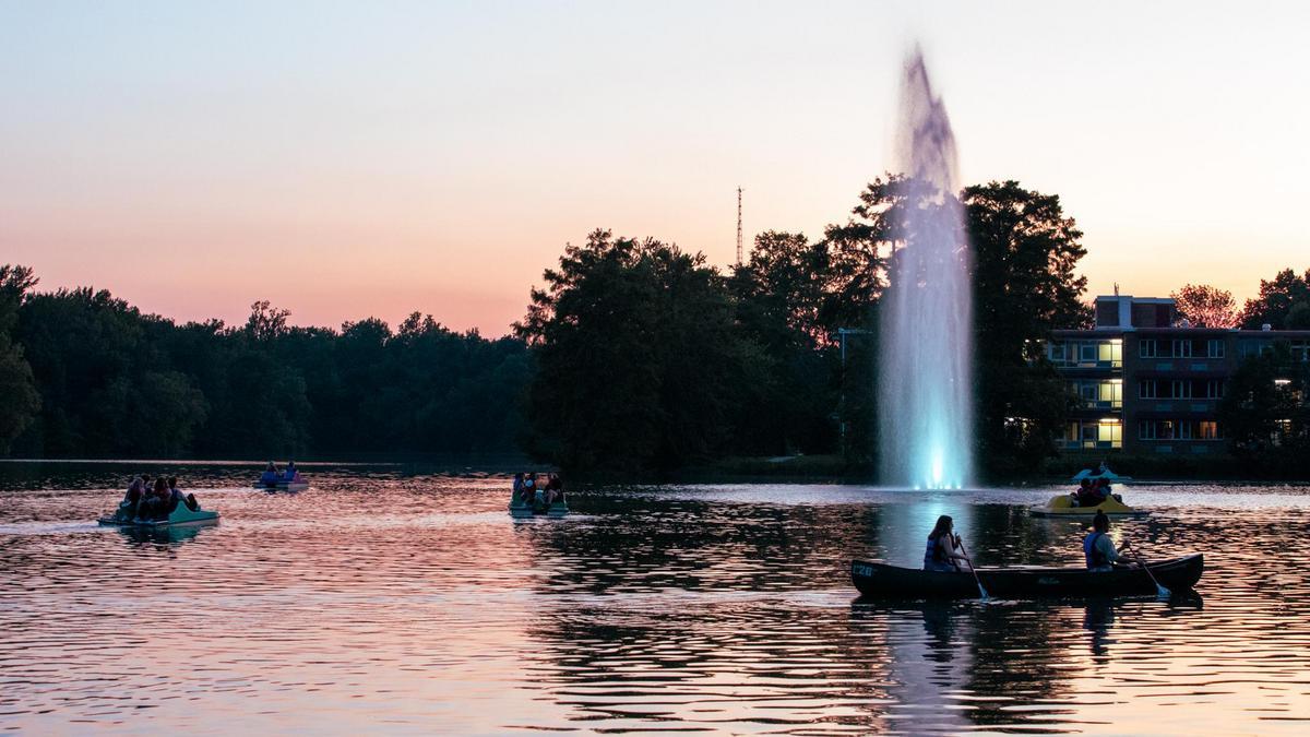 Campus Lake, at night. People are boating around the large fountain in the center.