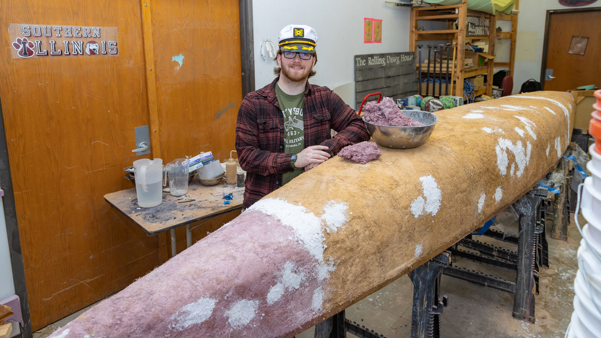 A student works on building a concrete canoe.