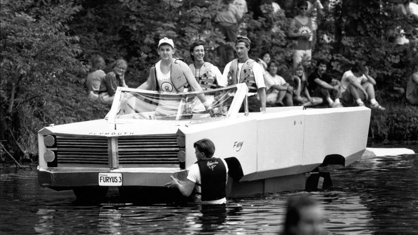 SIU students aboard their cardboard boat, shaped like a car.