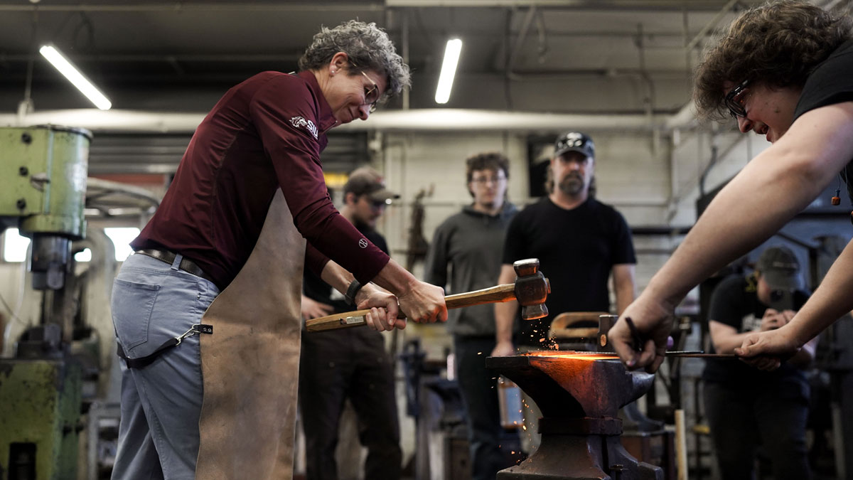 Molly Hudgins hammers on steel.