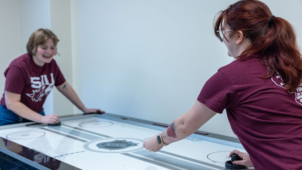 Two SIU students playing air hockey.