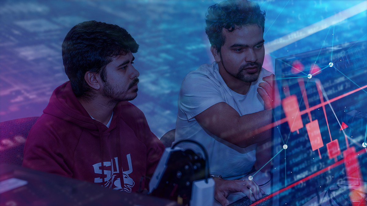 Two men are surrounded by computer codes and diagrams. There is a laptop behind her.